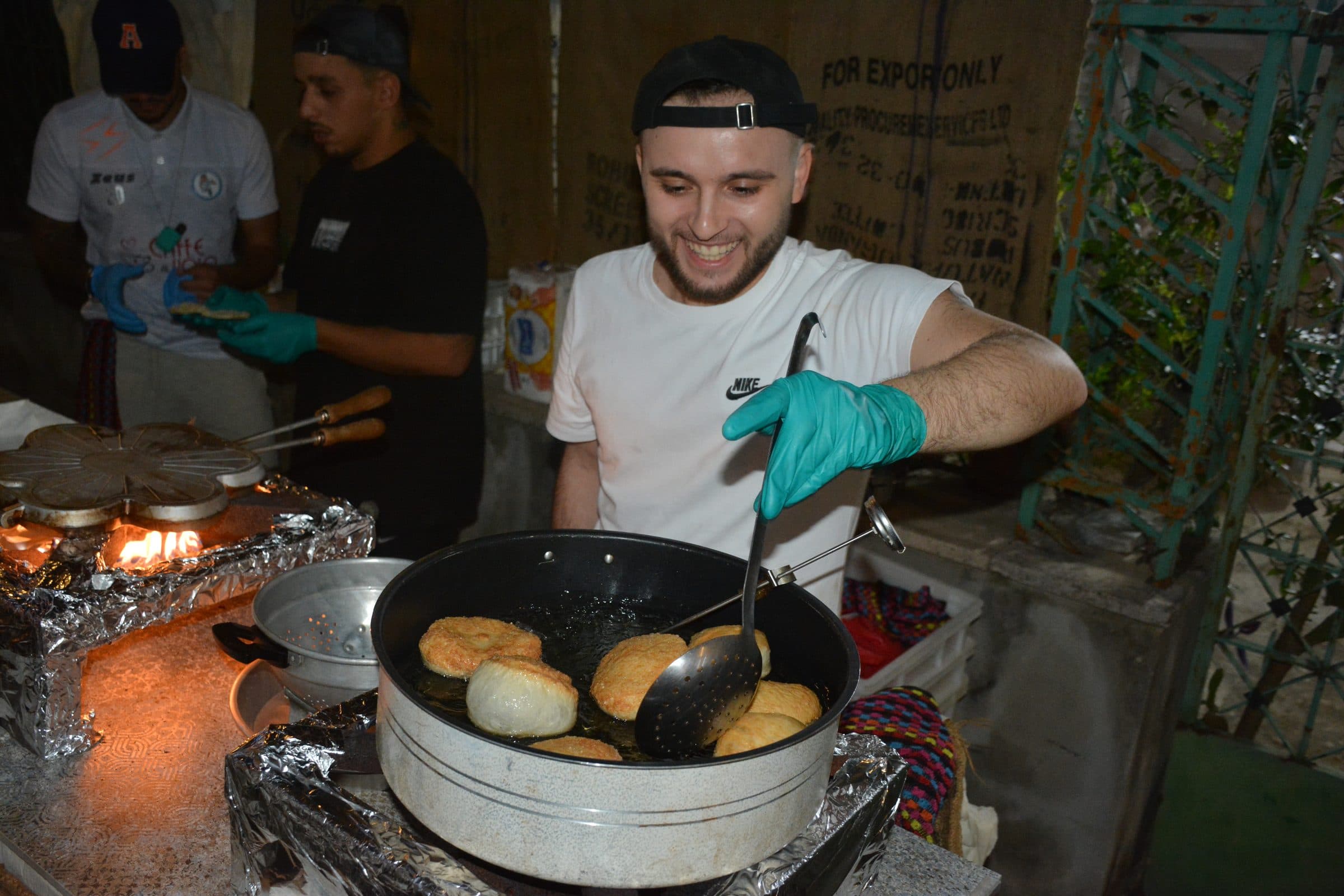 Uno stand che frigge, con la padella sul fuoco e le mani al lavoro